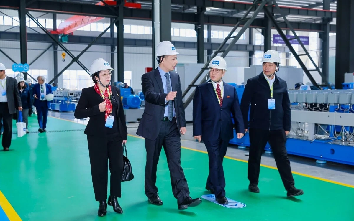 Guests in hard hats walking past extruders in the workshop