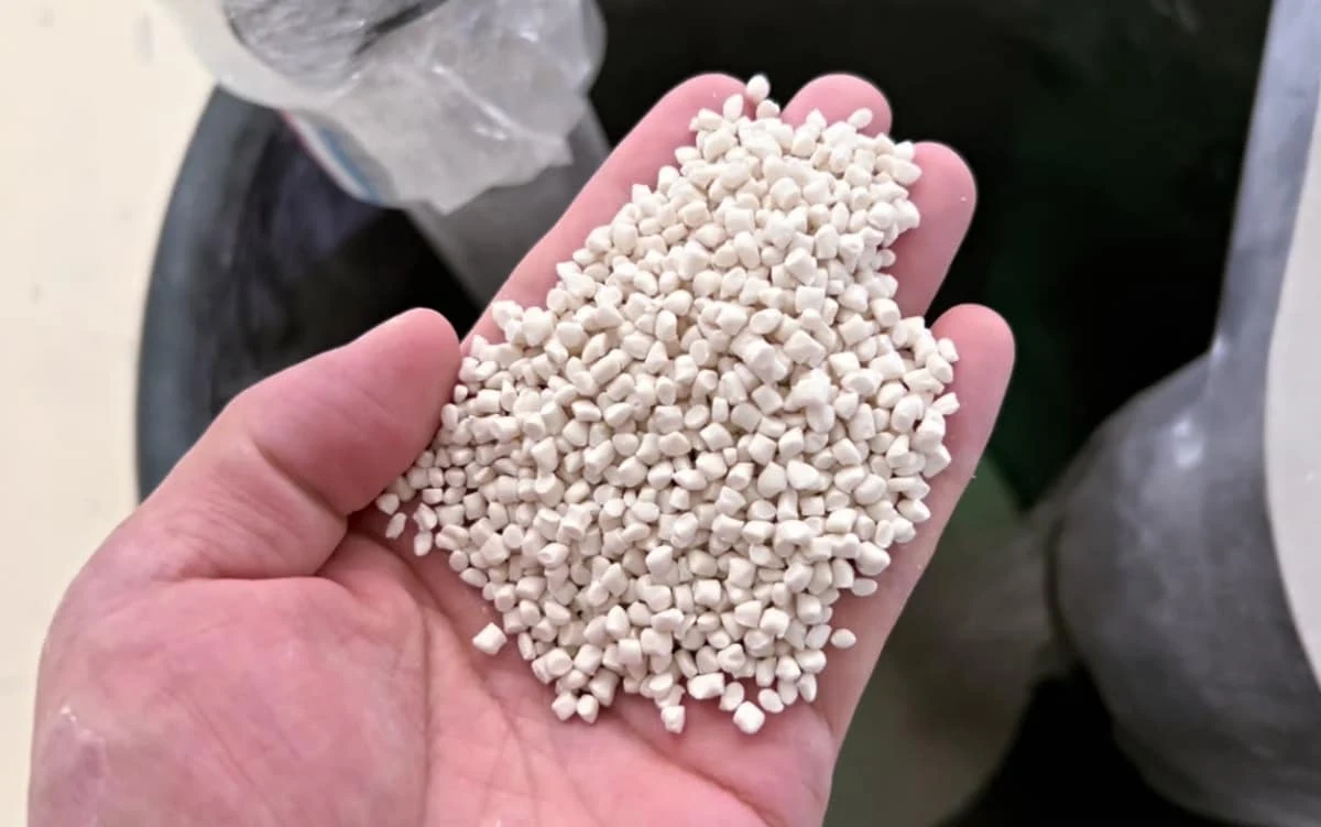 Pale PE/PP filler masterbatch pellets held in a hand from the SAT-T75 project